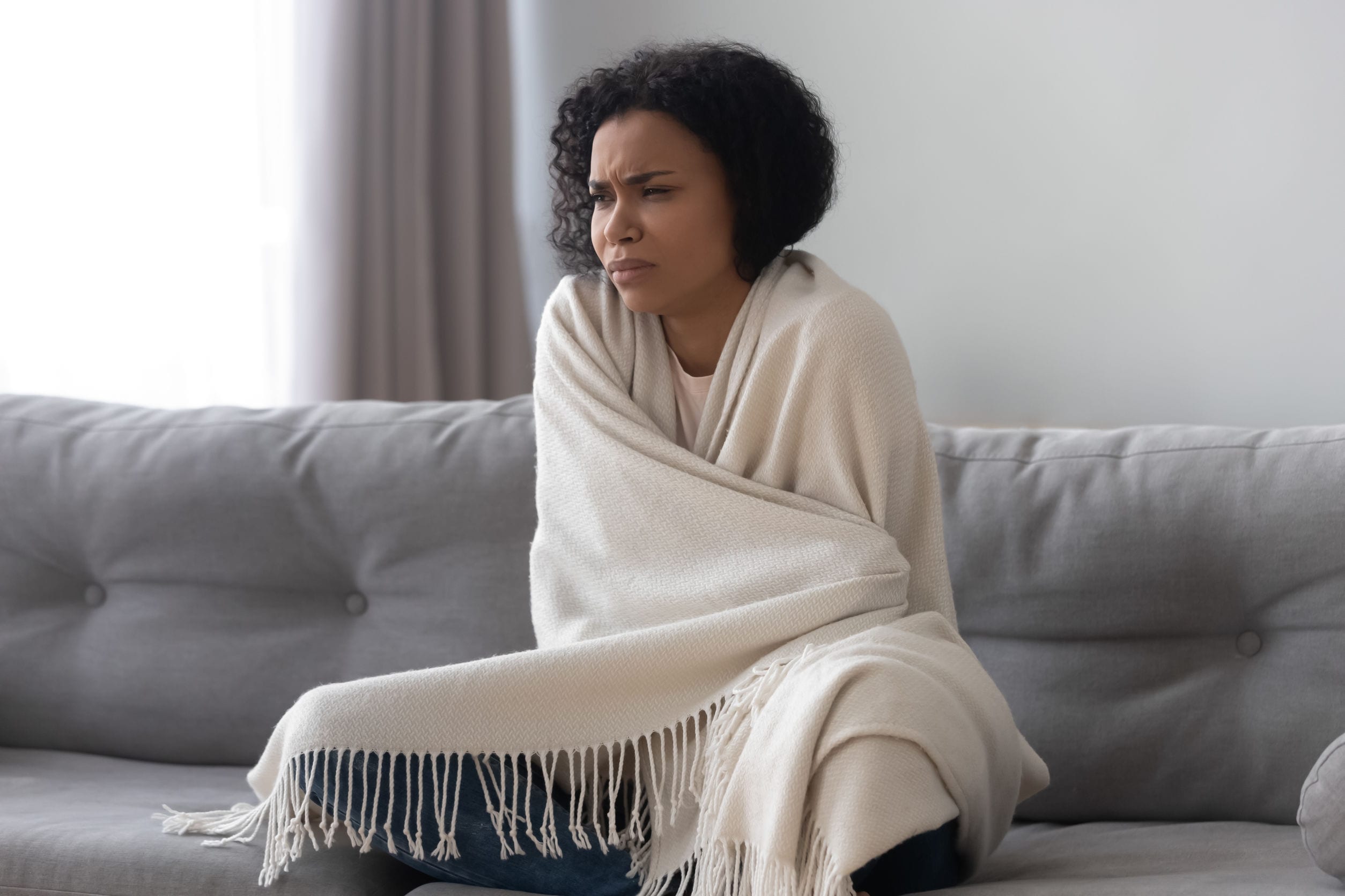 Unhappy African American woman feeling cold, covered with warm blanket NeroAC_HeatHelp